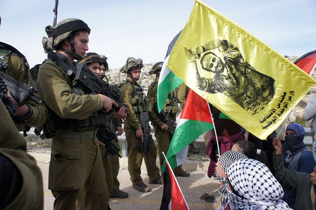 Israeli troops in the West Bank Palestinian town of Kafr ad-Dik. The yellow banner being waved at them in protest is a portrait of Marwan Barghouti  the hunger strike leader